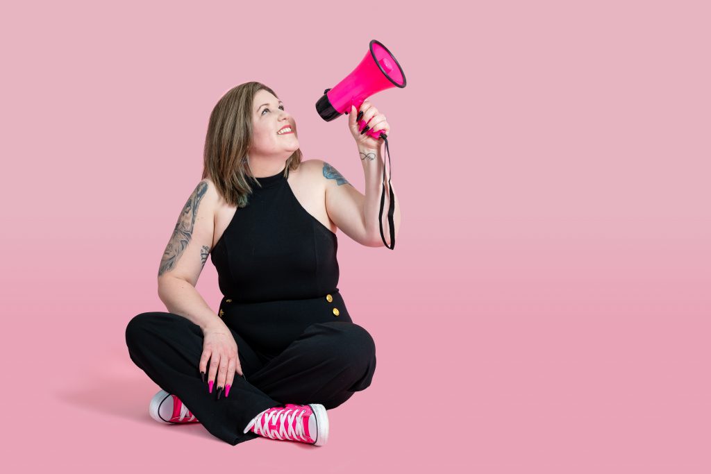 Amie sitting on the floor with a pink megaphone
