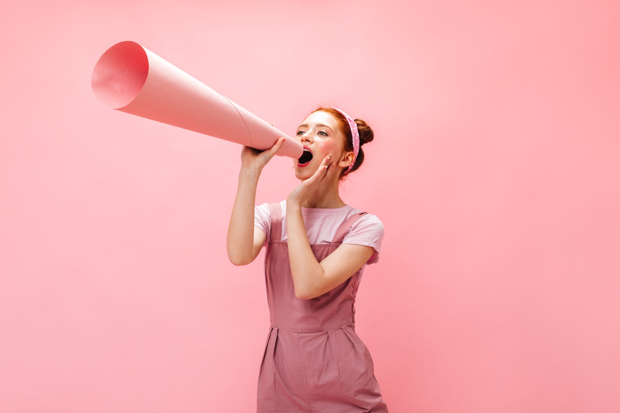 Young Woman Shouting into Pink Megaphone